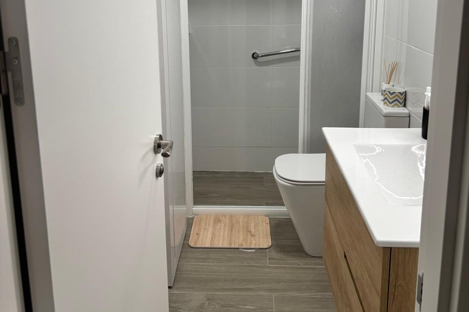 Baño reformado con mueble de madera y suelo imitación madera